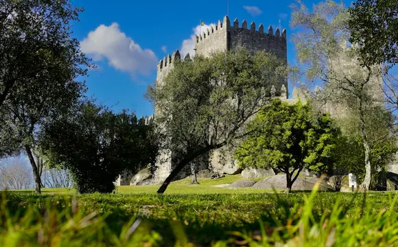 Guimarães Castle surrounded by grass and trees in Portugal.