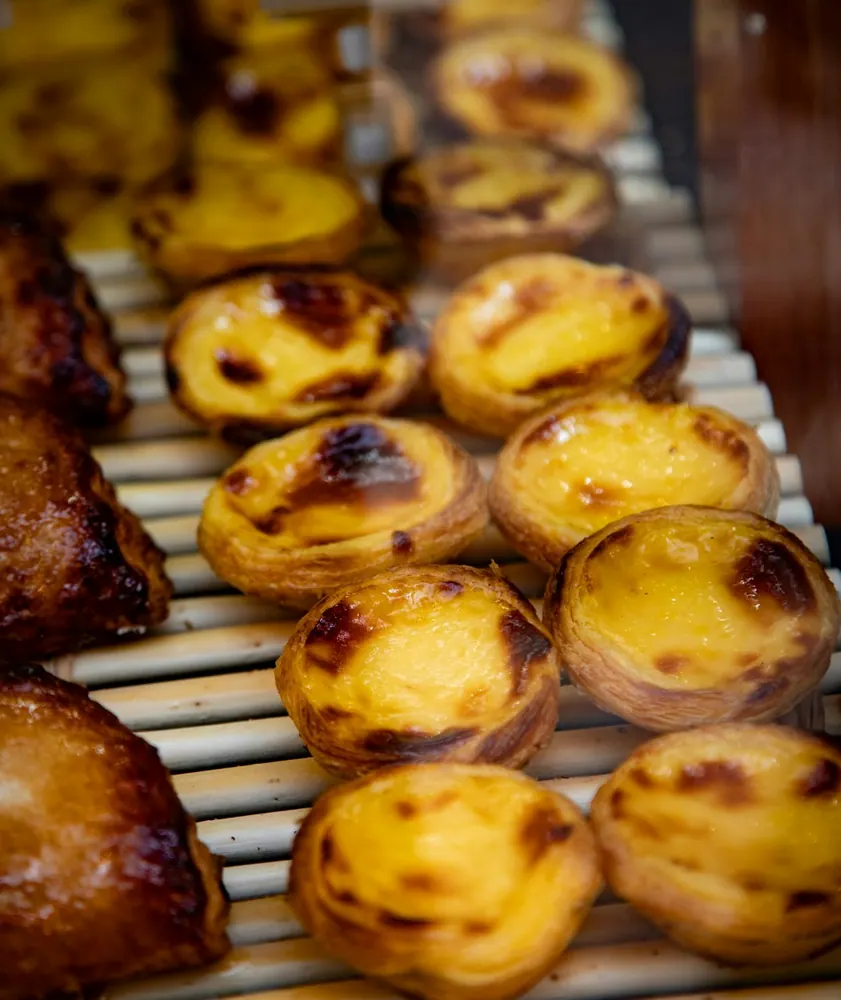 Portuguese custard tarts arranged on a bakery rack in Lisbon.