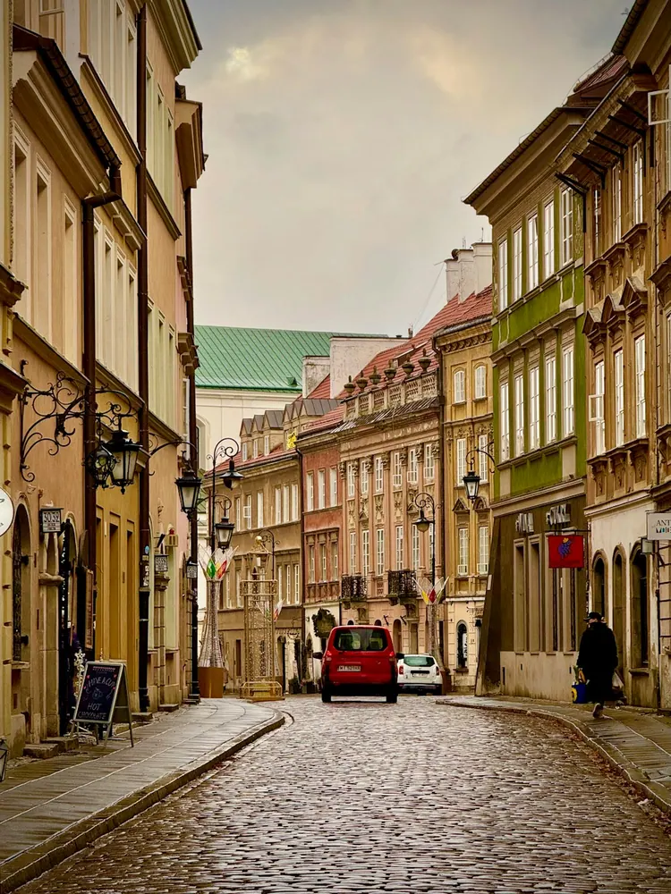 Cobblestone street lined with historic buildings in Warsaw Old Town.