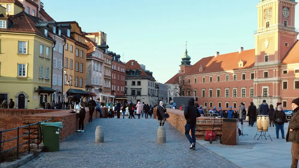 People walking across a historic square in Warsaw, Poland.