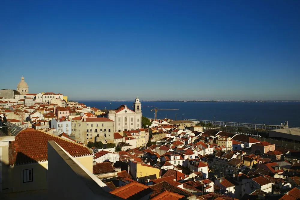 Historic rooftops and the Tagus River in Lisbon, Portugal. Destination context, not a photograph of this tour.