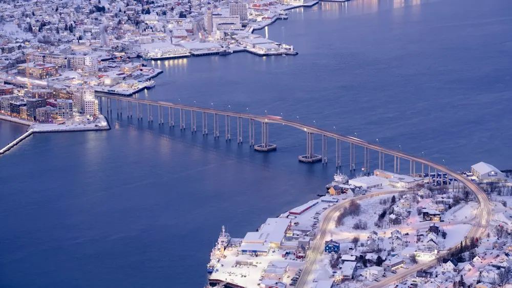 Tromsø Bridge and snowy waterfront at polar twilight in Norway.