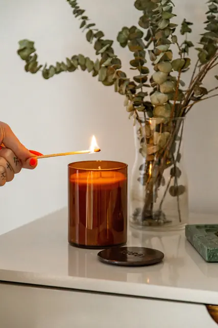 A lit candle on a table, creating a warm and cozy glow