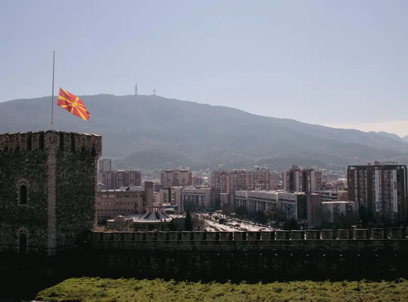 Scenic panoramic view of Skopje, North Macedonia, with the city surrounded by mountains under a clear sky.