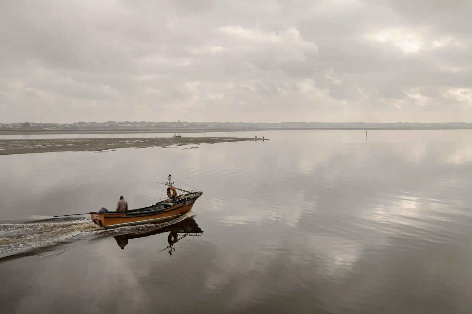 Small traditional boat navigating on the calm waters of the Aveiro Lagoon