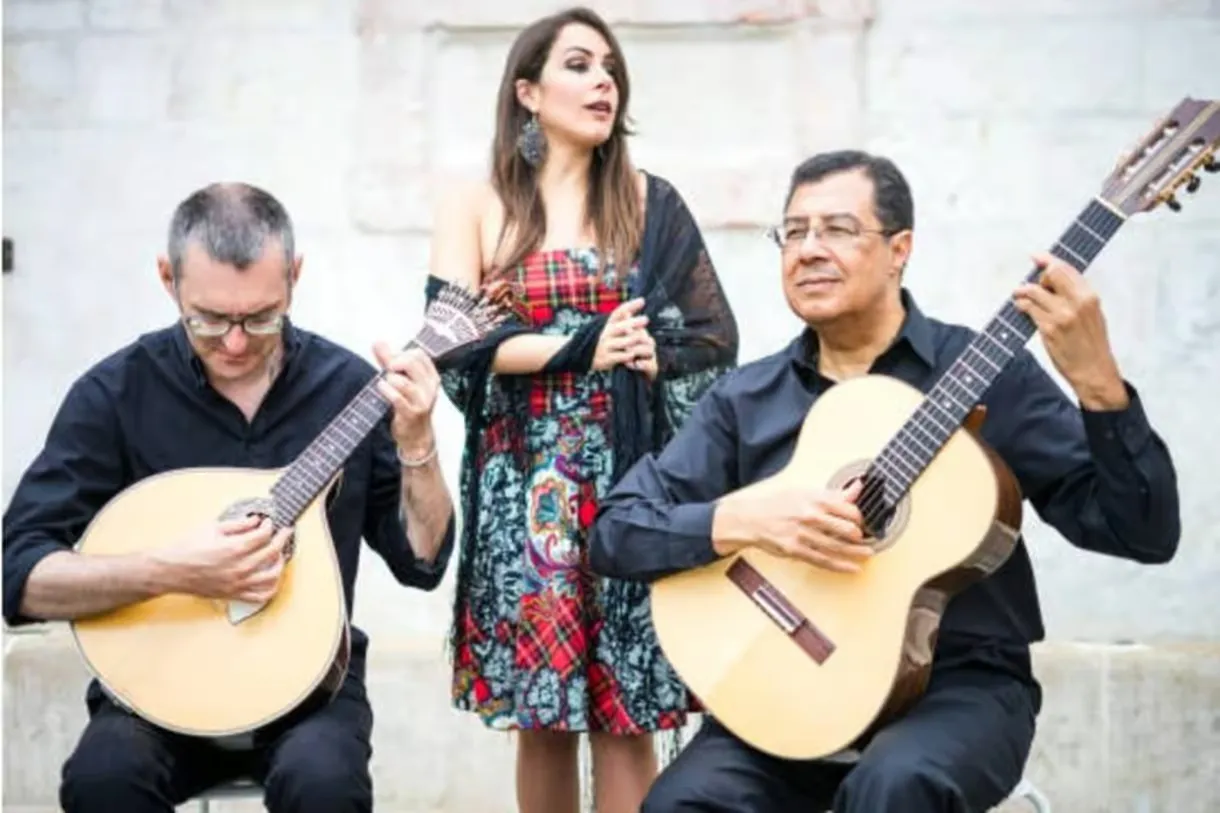A singer performing with two guitarists.