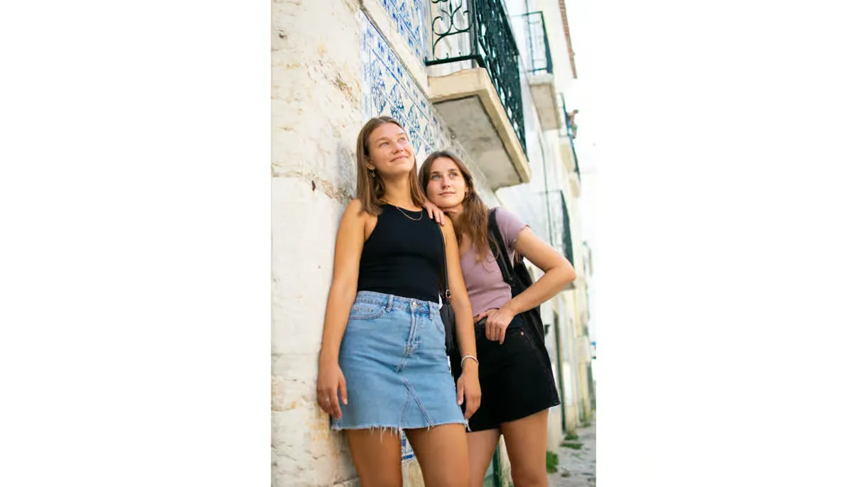 Two visitors posing together on a Lisbon street.