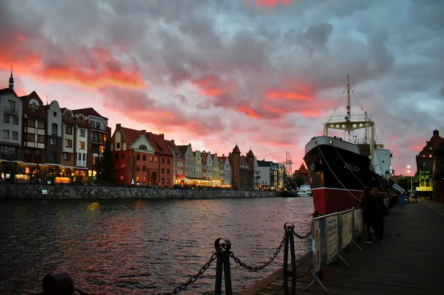 Gdańsk waterfront and a moored boat at sunset.
