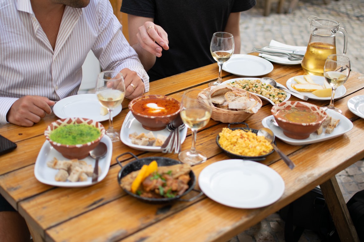 Portuguese dishes, bread and drinks on an outdoor table in Lisbon.
